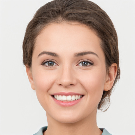 Joyful white young-adult female with medium  brown hair and grey eyes