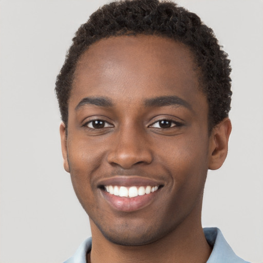 Joyful black young-adult male with short  brown hair and brown eyes