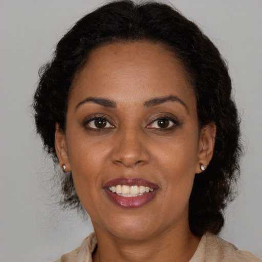 Joyful black adult female with long  brown hair and brown eyes