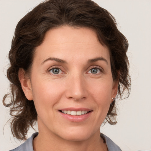 Joyful white adult female with medium  brown hair and grey eyes