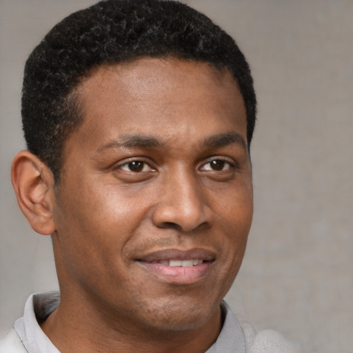 Joyful black young-adult male with short  brown hair and brown eyes