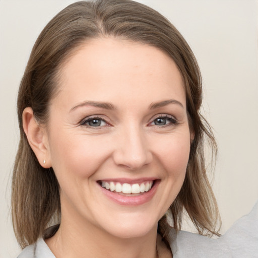 Joyful white young-adult female with medium  brown hair and grey eyes