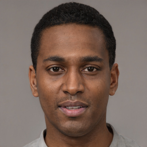Joyful black young-adult male with short  black hair and brown eyes