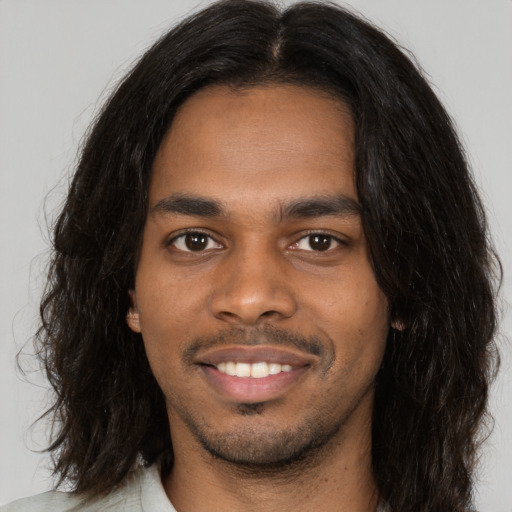 Joyful black young-adult male with long  brown hair and brown eyes