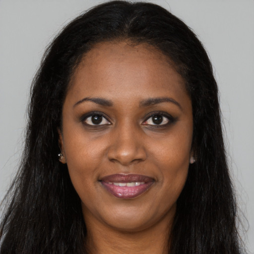 Joyful black young-adult female with long  brown hair and brown eyes