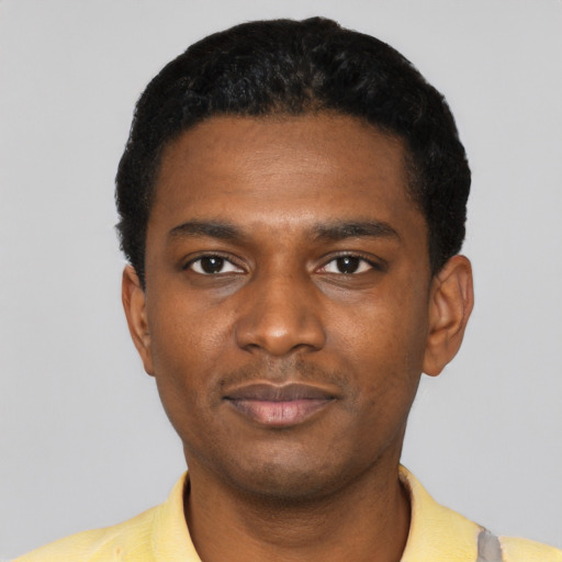 Joyful black young-adult male with short  black hair and brown eyes