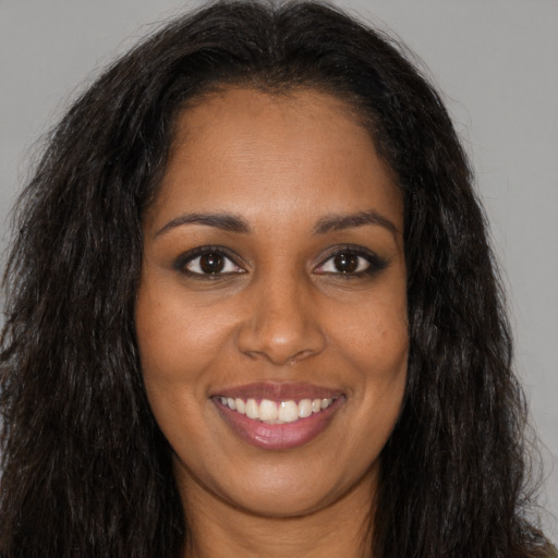 Joyful black young-adult female with long  brown hair and brown eyes