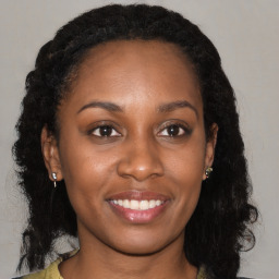 Joyful black young-adult female with long  brown hair and brown eyes