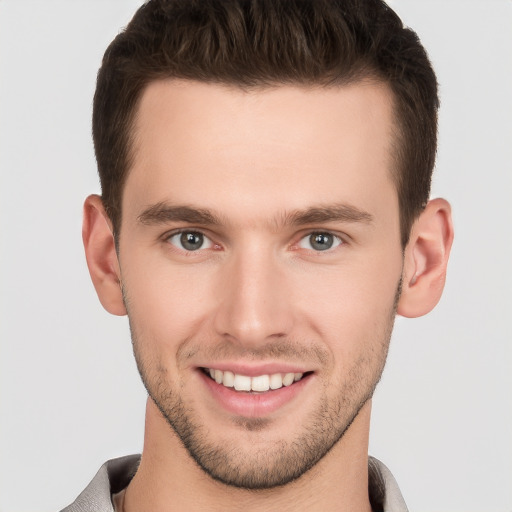 Joyful white young-adult male with short  brown hair and grey eyes