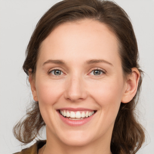 Joyful white young-adult female with medium  brown hair and grey eyes