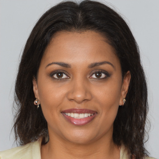 Joyful black young-adult female with long  brown hair and brown eyes
