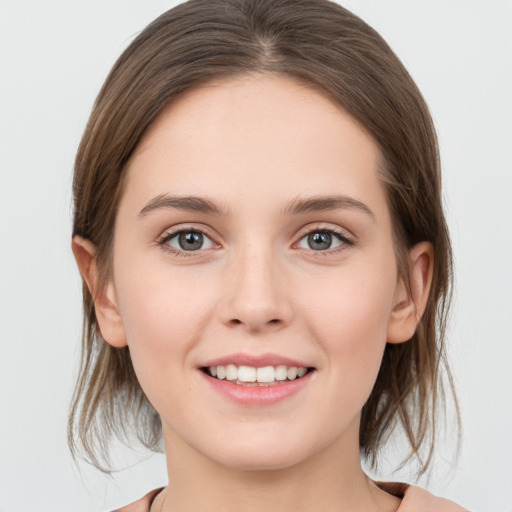 Joyful white young-adult female with medium  brown hair and grey eyes