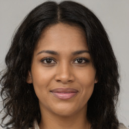 Joyful black young-adult female with long  brown hair and brown eyes