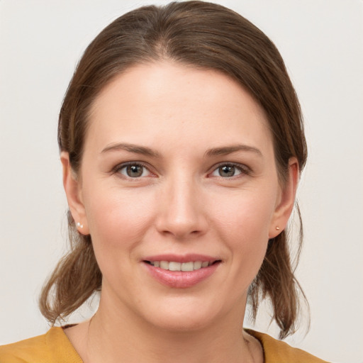 Joyful white young-adult female with medium  brown hair and grey eyes