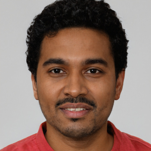 Joyful black young-adult male with short  black hair and brown eyes