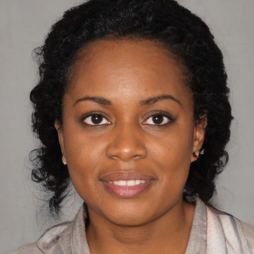 Joyful black young-adult female with long  black hair and brown eyes