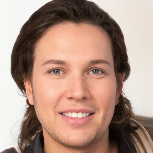 Joyful white young-adult male with long  brown hair and brown eyes