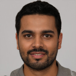 Joyful latino young-adult male with short  black hair and brown eyes