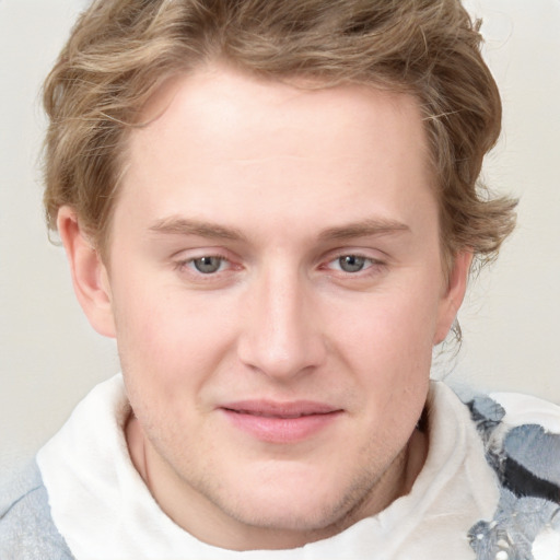 Joyful white young-adult male with short  brown hair and blue eyes