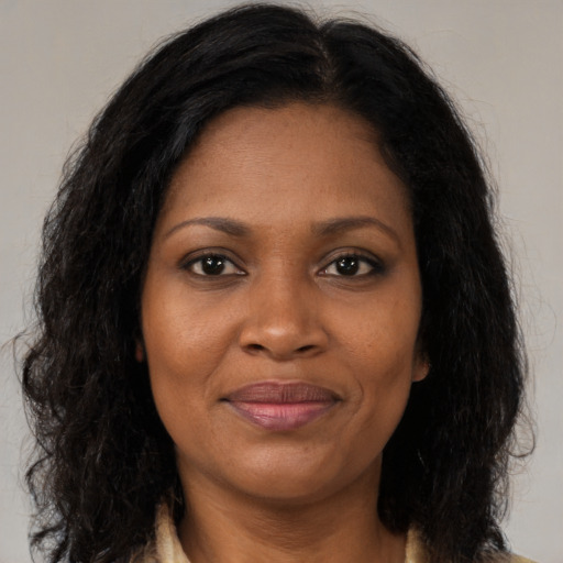 Joyful black adult female with long  brown hair and brown eyes