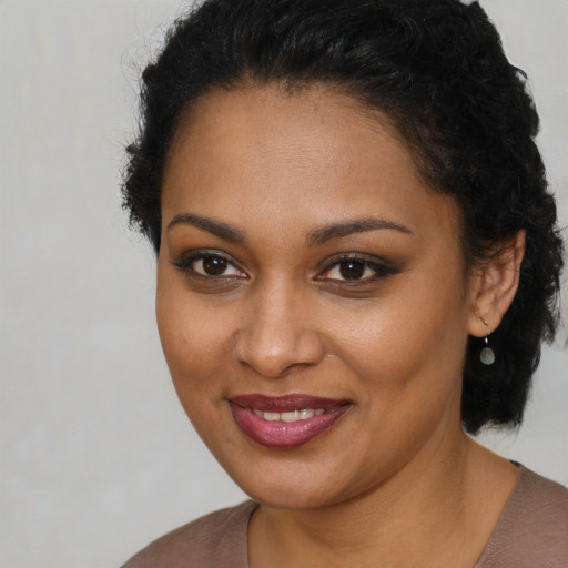 Joyful black young-adult female with long  brown hair and brown eyes