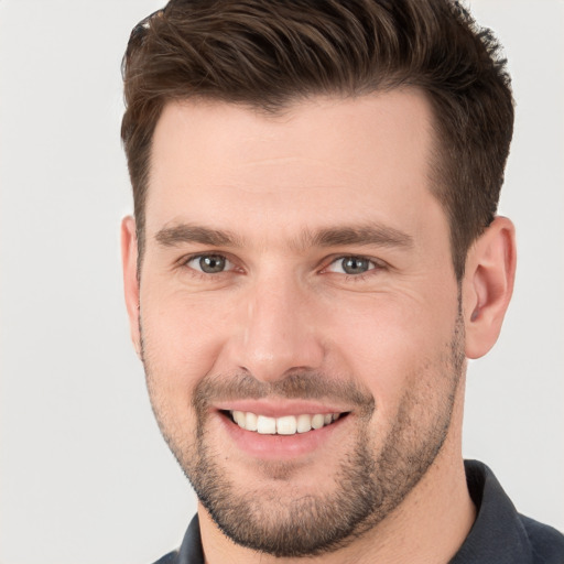 Joyful white young-adult male with short  brown hair and grey eyes