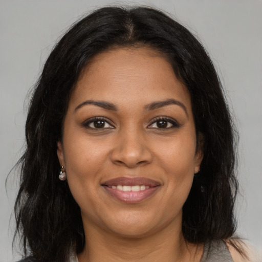 Joyful black young-adult female with long  brown hair and brown eyes