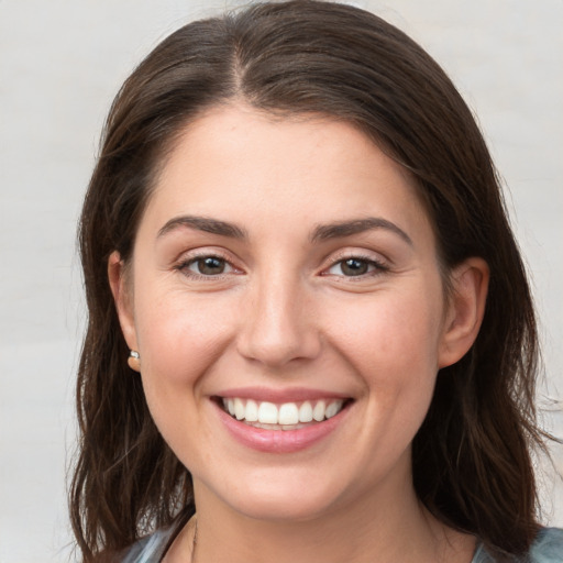 Joyful white young-adult female with medium  brown hair and grey eyes