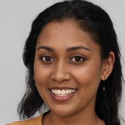 Joyful black young-adult female with long  brown hair and brown eyes