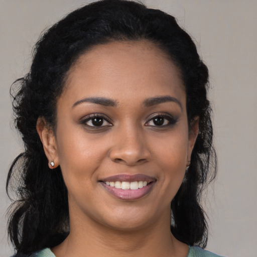 Joyful black young-adult female with long  brown hair and brown eyes