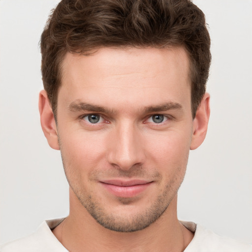 Joyful white young-adult male with short  brown hair and grey eyes