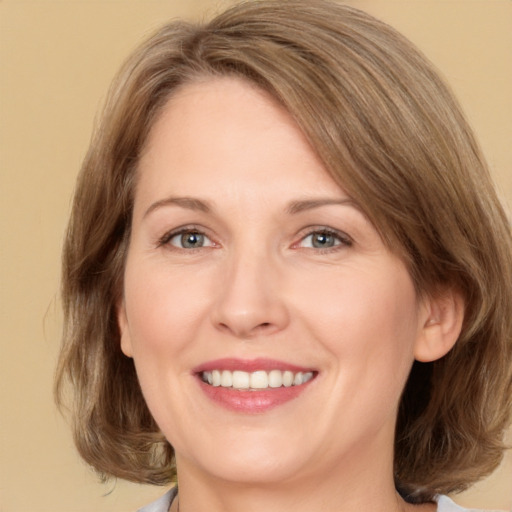 Joyful white adult female with medium  brown hair and green eyes