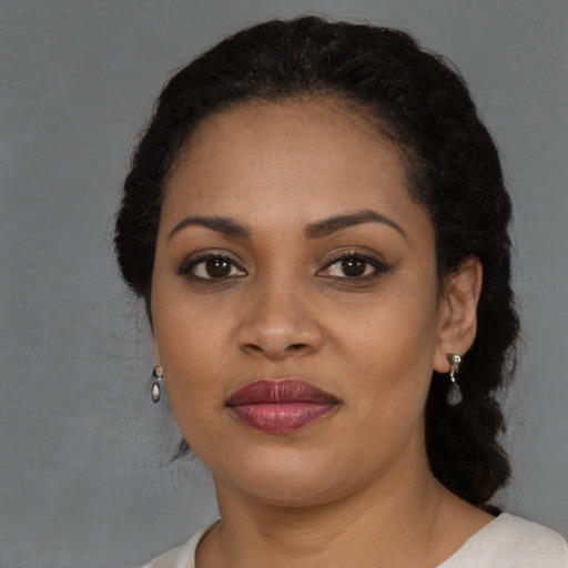 Joyful black young-adult female with long  brown hair and brown eyes