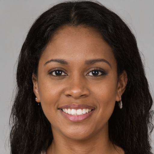 Joyful black young-adult female with long  brown hair and brown eyes