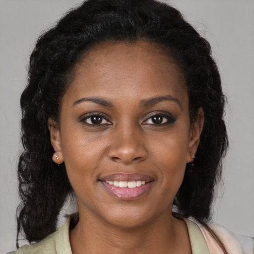 Joyful black young-adult female with long  brown hair and brown eyes