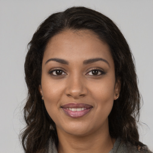 Joyful black young-adult female with long  brown hair and brown eyes