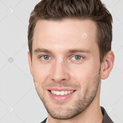 Joyful white young-adult male with short  brown hair and grey eyes