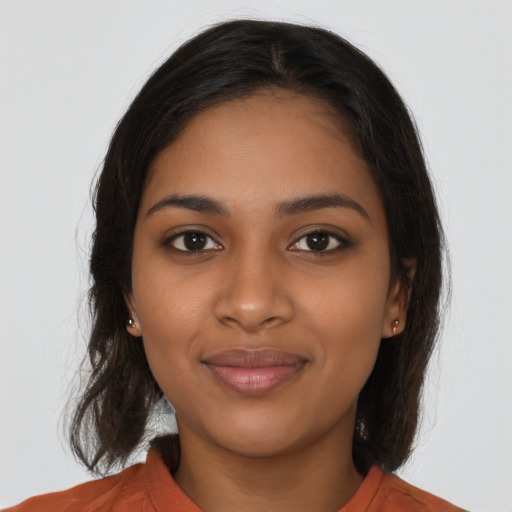 Joyful black young-adult female with long  brown hair and brown eyes