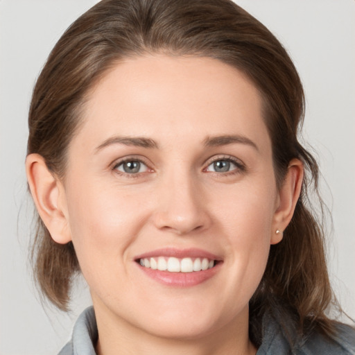 Joyful white young-adult female with medium  brown hair and grey eyes