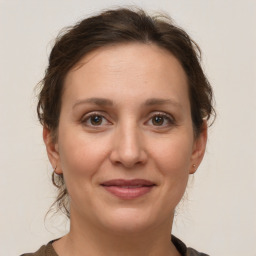 Joyful white young-adult female with medium  brown hair and grey eyes