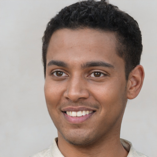 Joyful black young-adult male with short  brown hair and brown eyes