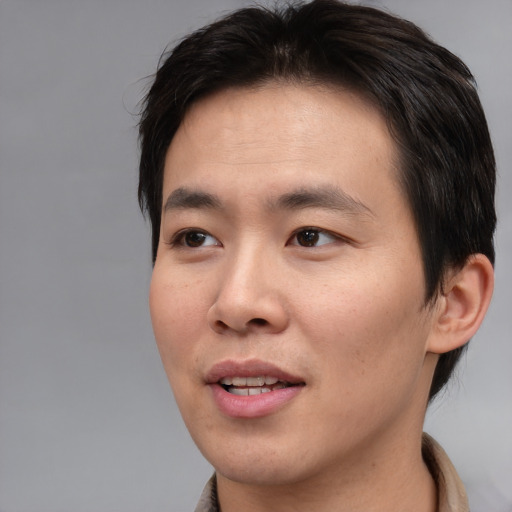 Joyful asian young-adult male with short  brown hair and brown eyes