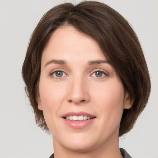 Joyful white young-adult female with medium  brown hair and grey eyes