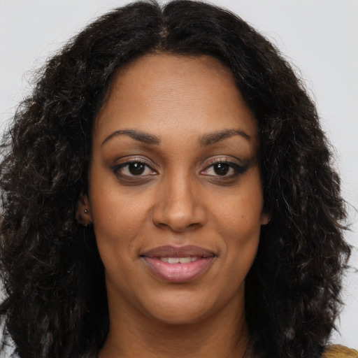 Joyful black adult female with long  brown hair and brown eyes