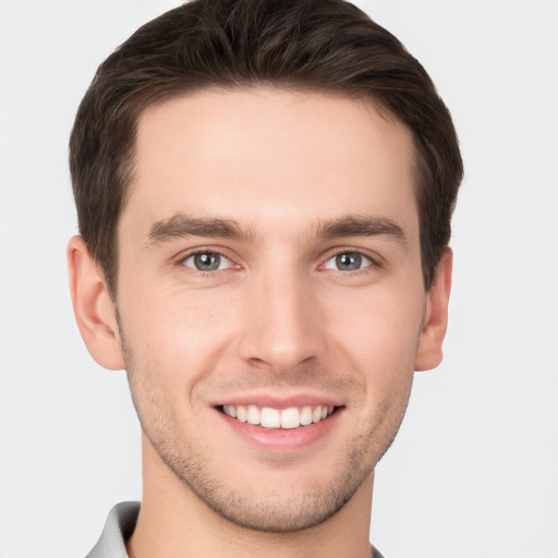 Joyful white young-adult male with short  brown hair and grey eyes