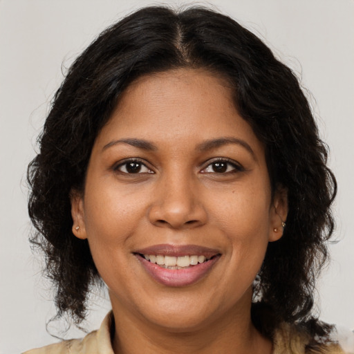 Joyful black young-adult female with long  brown hair and brown eyes