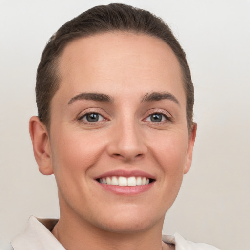 Joyful white young-adult female with short  brown hair and grey eyes