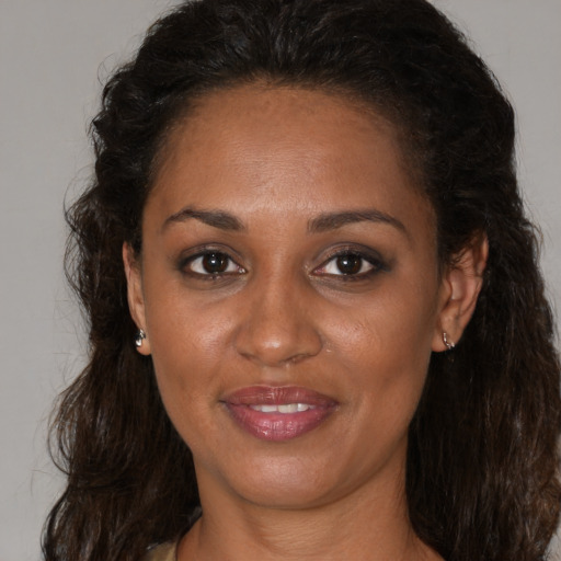 Joyful black young-adult female with long  brown hair and brown eyes