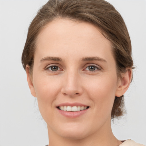 Joyful white young-adult female with medium  brown hair and grey eyes