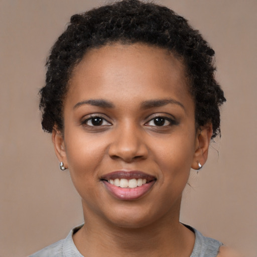 Joyful black young-adult female with short  black hair and brown eyes
